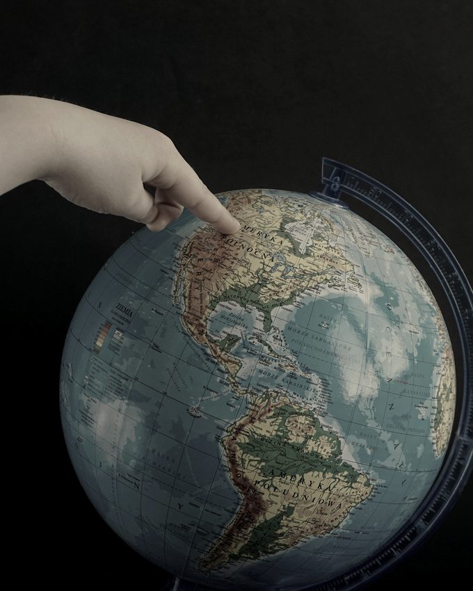 A hand indicating North America on a globe